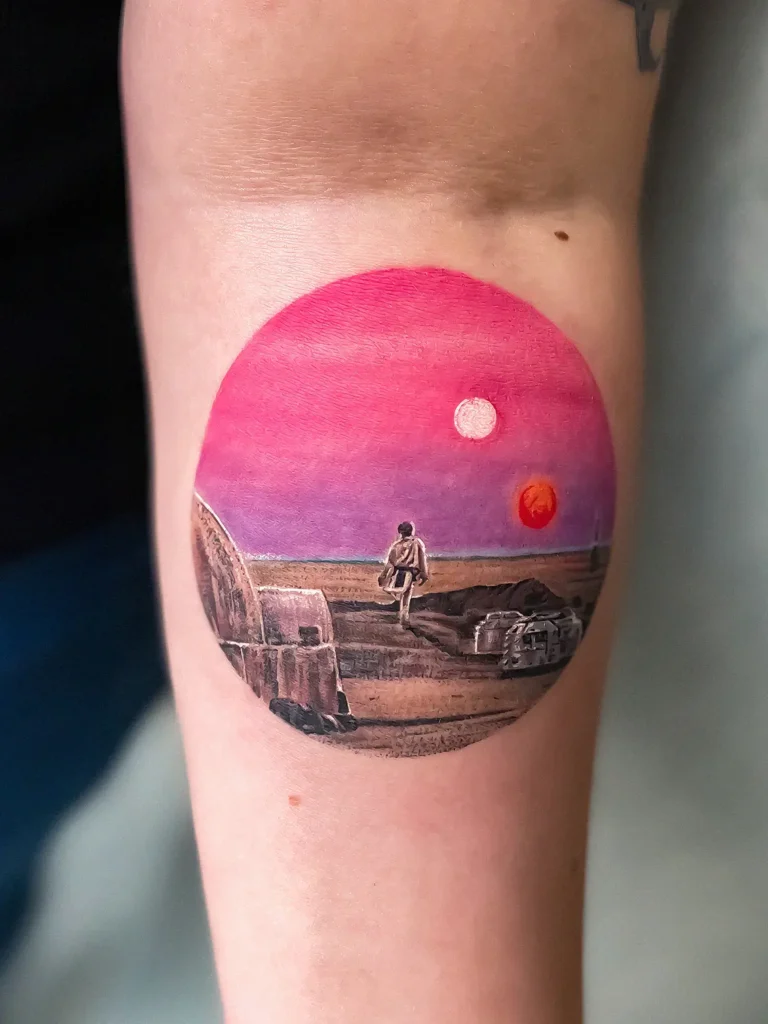 Rund tatovering med motiv landskab med en solnedgang.